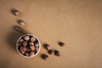 Wall Mural - Pile of hazelnuts filbert in a bowl on a brown background. Fresh nuts in their shells.