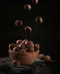 Wall Mural - Pile of hazelnuts filbert in a wooden bowl on a dark wooden background