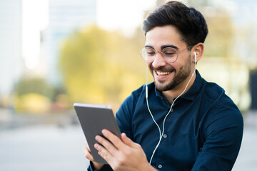 Young man having a video call on digital tablet outdoors.