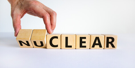 Wall Mural - Nuclear or clear symbol. Businessman turns a cube and changes the word 'nuclear' to 'clear'. Beautiful white background. Nuclear or clear and business concept. Copy space.
