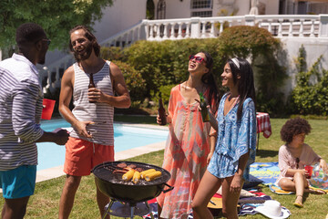 Diverse group of friends having barbecue and talking at a pool party