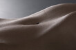 Closeup of the abdomen of a sexy naked woman against a gray background