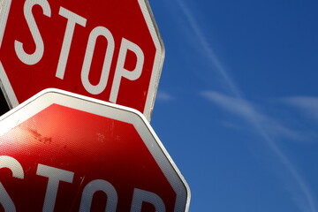 Two stop signs on blue sky