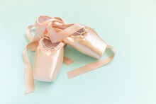 New Pastel Beige Ballet Shoes With Satin Ribbon Isolated On Blue Background. Ballerina Classical Pointe Shoes For Dance Training. Ballet School Concept. Top View Flat Lay, Copy Space