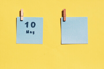 May 10st . Day of 10 month, calendar date. Two blue sheets for writing on a yellow background. Top view, copy space. Spring month, day of the year concept