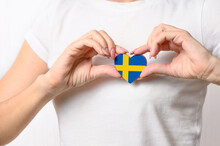 Love Sweden. The Girl Holds A Heart In The Form Of The Flag Of Sweden On Her Chest. Swedish Patriotism Concept