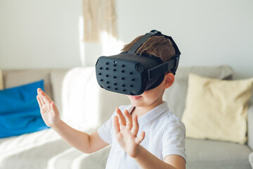 Little cute boy looks at virtual reality with glasses. Happy child. Fun.