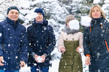 family portrait in the winter forest, parent and children, they throw snow, beautiful nature with bright snowy fir trees