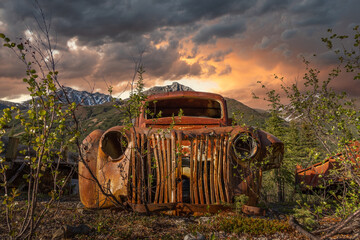 Abandoned 1940s style rusty truck that sits in the Yukon Territory wilderness in northern Canada. Seen in the summer time with midnight sun and stormy clouds building behind. 