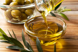 Fototapeta  - Pour olive oil into a glass bowl set against a wooden background