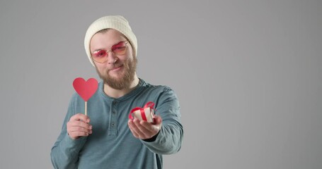 Poster - Handsome man with red heart and gift on grey background