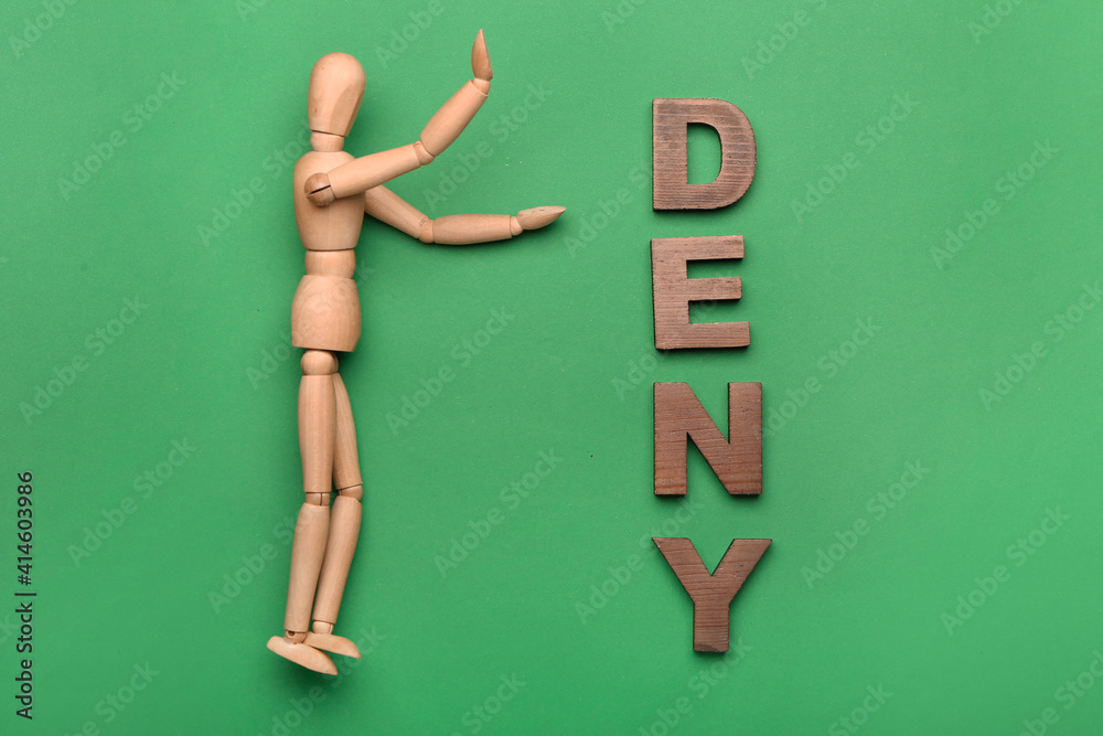 Wooden mannequin with word DENY on color background