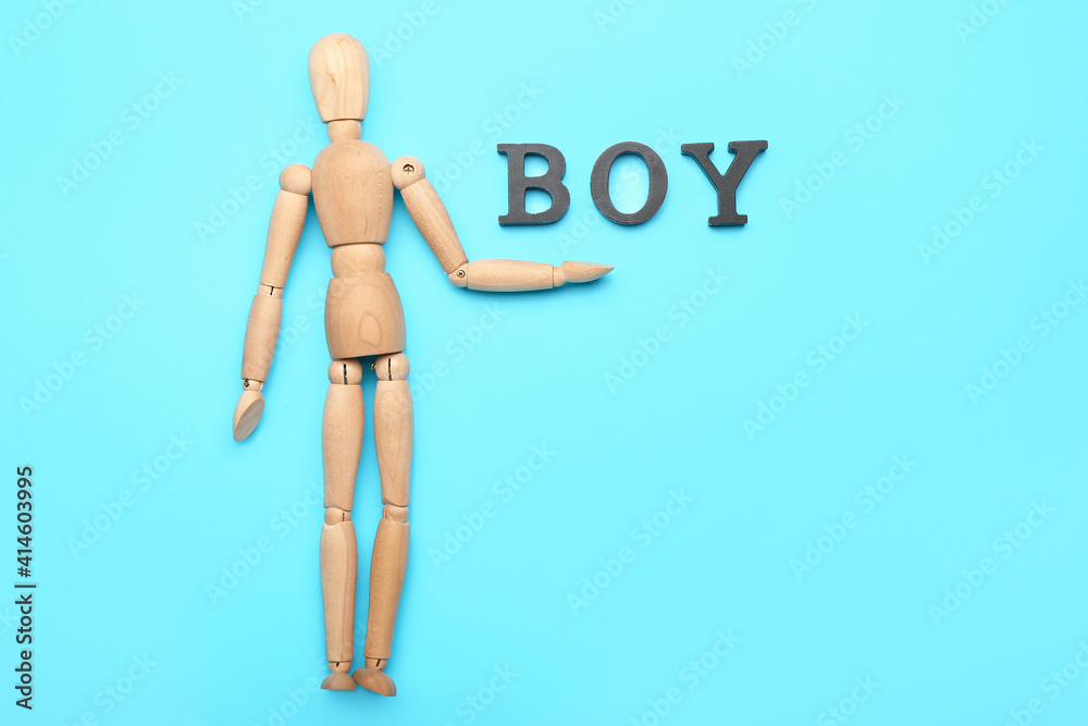 Wooden mannequin with word BOY on color background