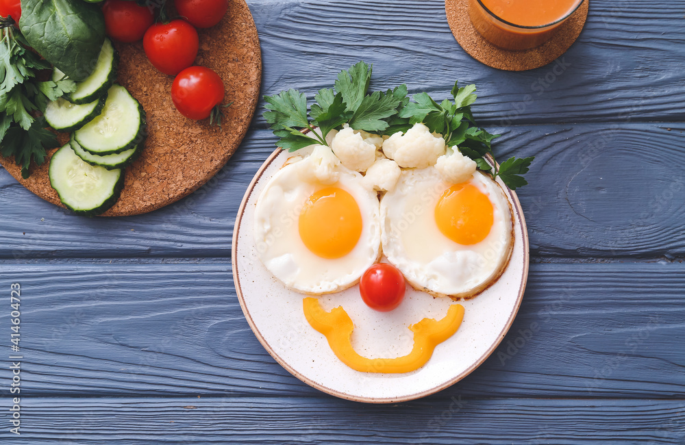 Creative breakfast for children with eggs and fresh vegetables on wooden background