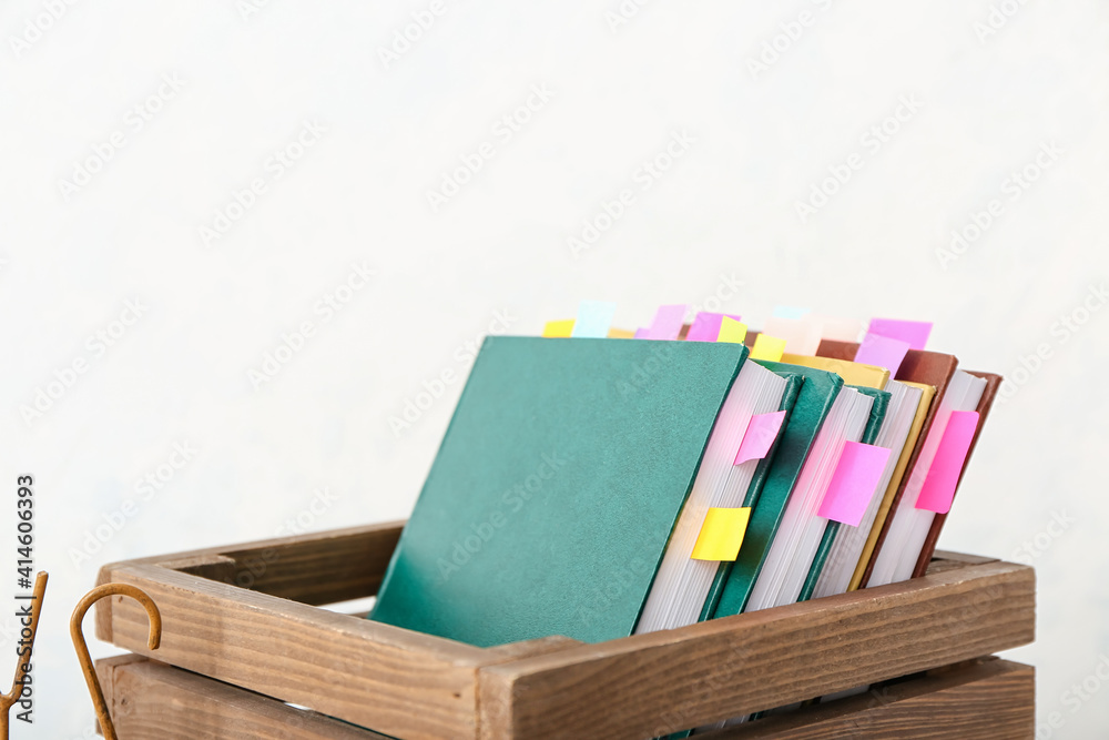 Many books with bookmarks in box on light background
