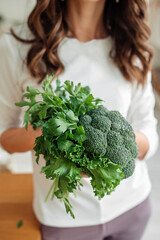 unrecognizable woman in white clothes holds in hands fresh green products, parsley, arugula and salad greens in hands. nutritionist food wellness blog vertical content, selective focus