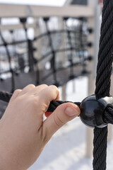 The hand holds the rope on the playground