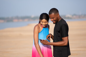 two young africans smiling while looking at a phone together