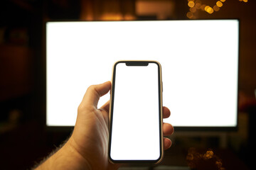 Photo of the white blank screen of the computer and hand holding cellphone. Digital web space concept