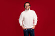 © deagreez - Photo portrait of cheerful old man wearing glasses warm white knitted sweater isolated on red color background