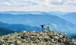 © anatoliy_gleb - Happy couple holding hands up, standing on top of cliff, beautiful mountains scenery on background. Hiking, tourists reaching peak together. Wild nature with amazing views. Sport tourism concept.