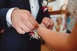 The groom ties a corsage on wrist with flowers on the bride's hand, close up.
