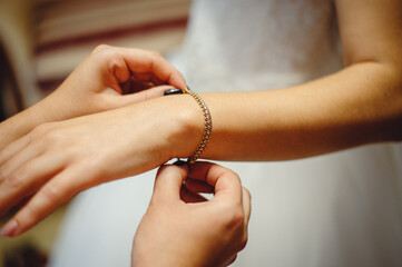 Wall Mural - Bridesmaid preparing bride for the wedding day, helping fasten her dress and fasten the bracelet. Bride morning before wedding ceremony. Film noise 