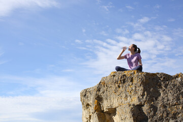 Yogi drinking water after yoga exercises in a cliff