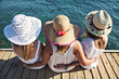 Three women with big hats at a beach for a summer party