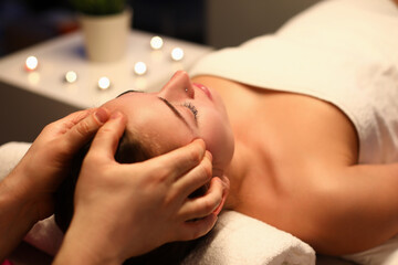 Wall Mural - Woman is given rejuvenating facial massage in an aroma room. Relaxing facial massage techniques concept