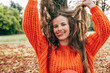 © iuricazac - Candid image of a gorgeous young woman has playful expression in the park. Female wearing an orange sweater has joyful expression on the nature background.