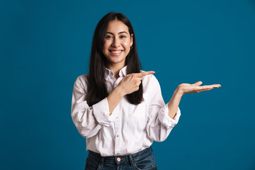 Happy beautiful asian girl holding and pointing finger at copyspace