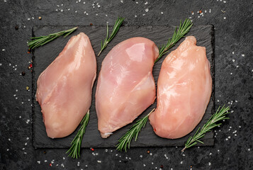 Wall Mural - raw chicken breast on a cutting board with spices on a stone background