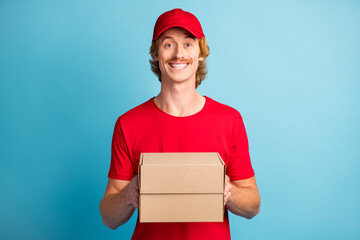 Sticker - Photo of positive handsome person arms holding boxes toothy smile look camera isolated on blue color background