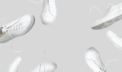 Flying white leather womens sneakers isolated on gray background, different kind. Fashionable stylish sports casual shoes. Creative minimalistic layout with footwear. Advertising for shoe store, blog