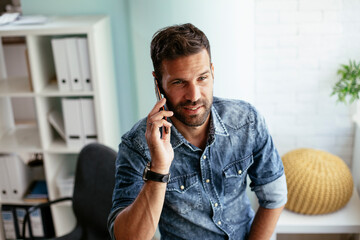 Wall Mural - Businessman in office using the phone. Young businessman talking to the phone