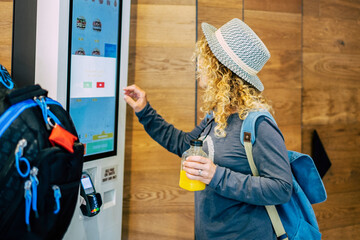 Woman make food order in modern display at fast food restaurant - self-service panel technology and people in travel lifestyle taking hamburger to eat