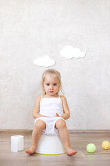 A little baby girl is sitting on a potty.