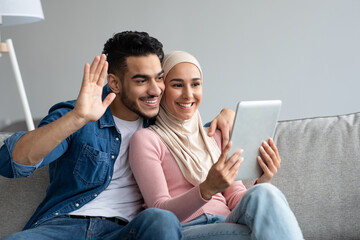 Wall Mural - Middle-eastern man and woman waving at digital tablet screen