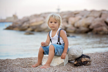 Wall Mural - Blond toddler child, boy, playing on the beach in the evening