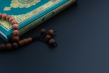 Holy Quran with arabic calligraphies translation meaning of Al-Quran and Rosary or Tasbih on black background. Ramadan,Hajj, Islamic and Copy Space concept