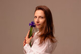 Fototapeta Tulipany - international womens day, mothers day, young girl holding a flower in her hand near her face, white shirt, color background

