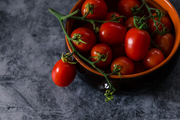 fresh tasty cherry tomatoes on dark stone background with copy space