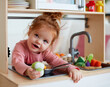 cute toddler baby girl playing on toy kitchen at home