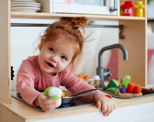 Cute Toddler Baby Girl Playing On Toy Kitchen At Home