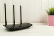 Black WiFi router in living room on a white table. Internet communication concept.