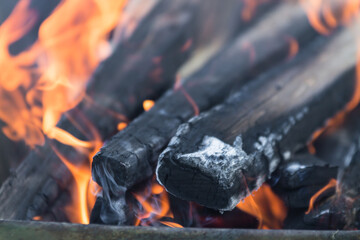 defocused orange flame of a campfire for barbecue in summer on green grass background