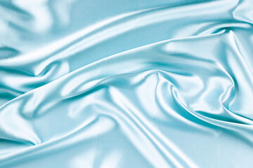Wall Mural - Beautiful light blue background with drapery and wavy folds of silk satin material texture. Top view