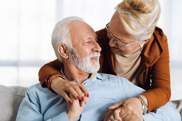 Wall Mural - Happy mature couple sitting on sofa and communicating