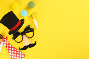 Wall Mural - Flat lay composition with clown mask and tie on yellow background. Space for text